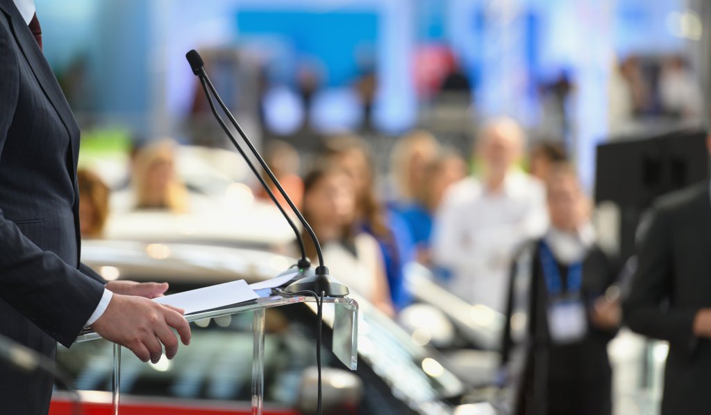 Politician speaking publicly from a stand.